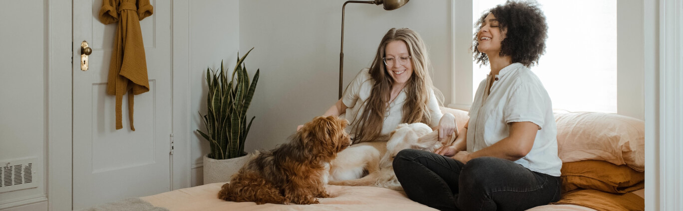 two women sitting on bed with dog