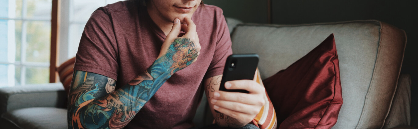 man with tattos looking at phone