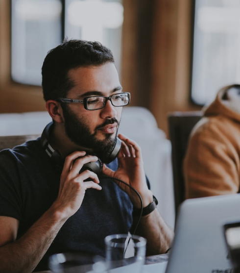 man looking at laptop with headphones around neck