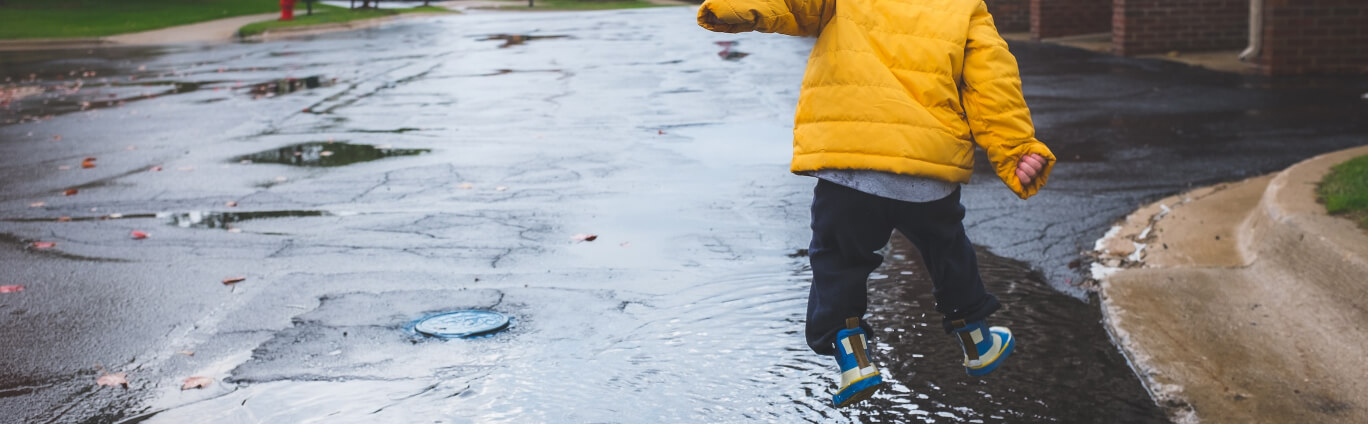 kid playing in a puddle